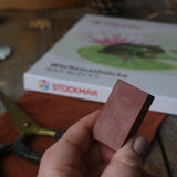 Brown Stockmar wax crayon block in an adult's hand.