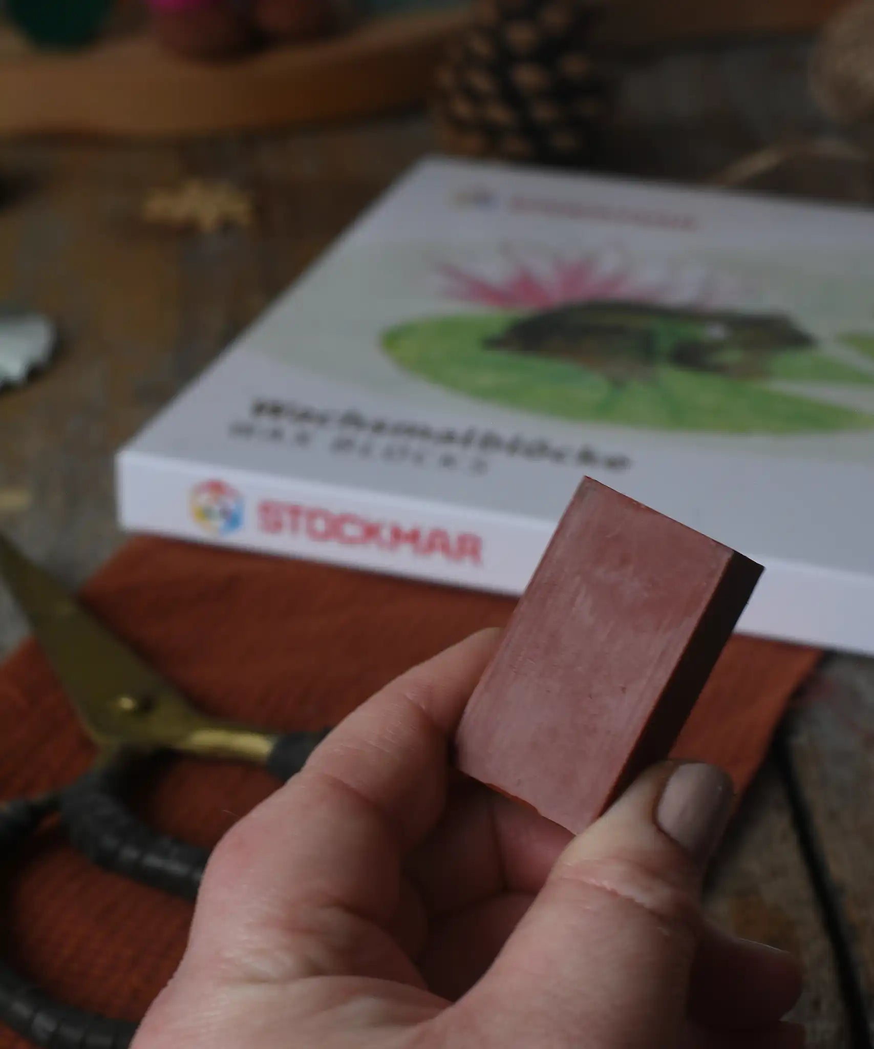 Brown Stockmar wax crayon block in an adult's hand.