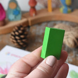 Green Stockmar wax crayon block in an adult's hand.