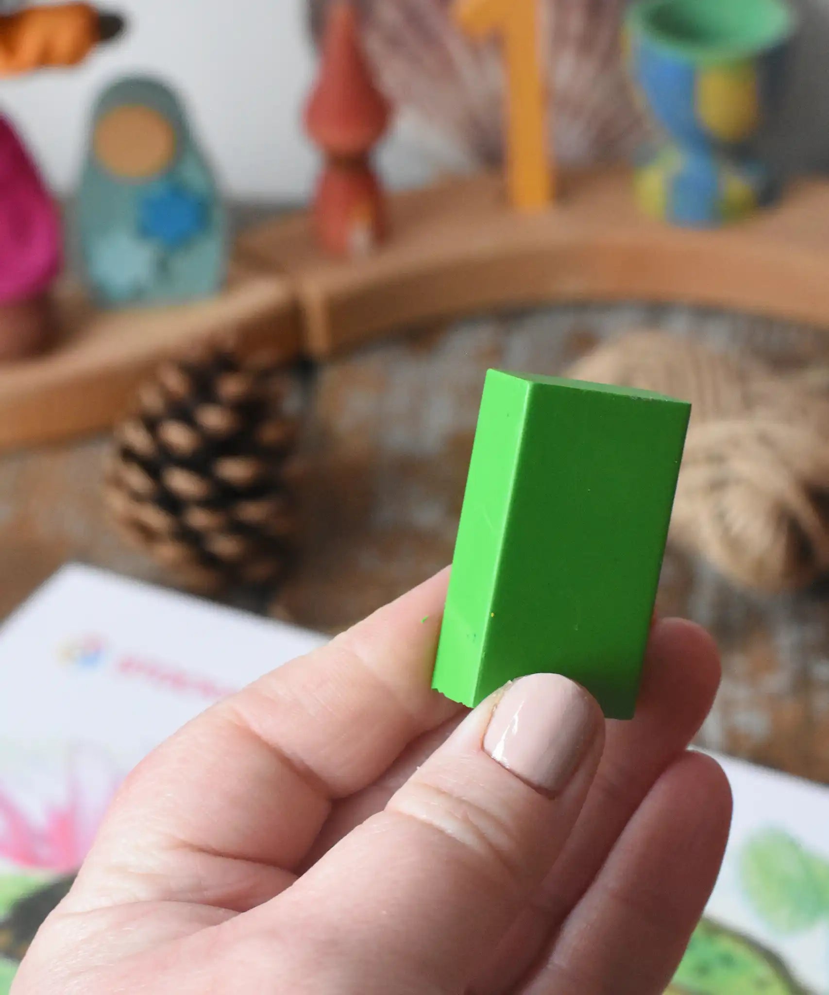 Green Stockmar wax crayon block in an adult's hand.