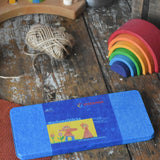 Stockmar 16 colour wax blocks set in a metal storage tin placed on a wooden paint splatterd desk.