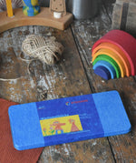 Stockmar 16 colour wax blocks set in a metal storage tin placed on a wooden paint splatterd desk.