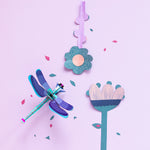 Studio Roof Jade Dragonfly made from biodegradable recyclable cardboard on a pink background with paper flowers