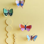 Collection of Studio Roof butterfly and insect decorations on a yellow pastel coloured wall