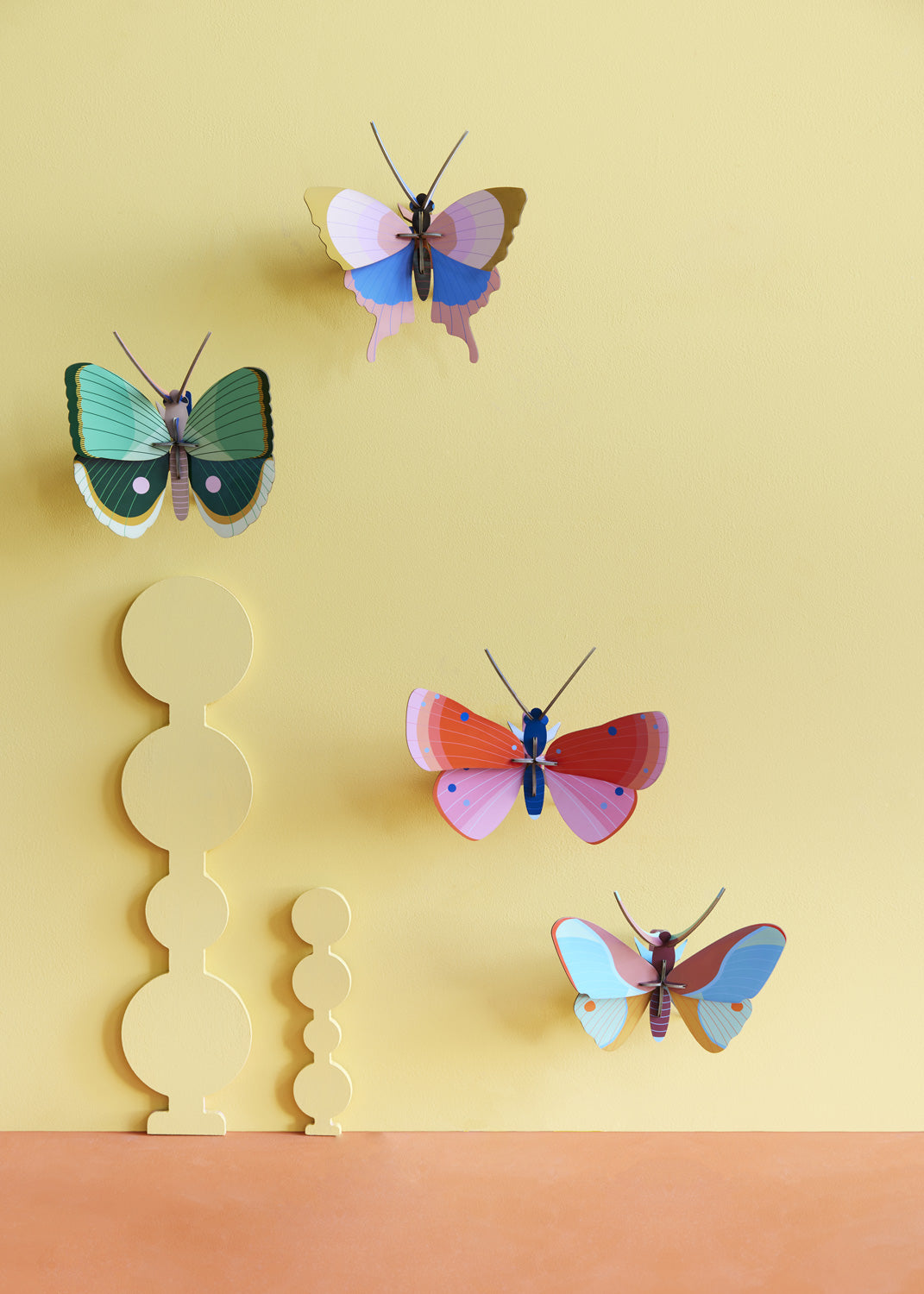 Collection of Studio Roof butterfly and insect decorations on a yellow pastel coloured wall