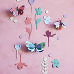 Studio Roof card butterfly wall hangings on a pink wall surrounded by card leaves