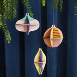 Studio Roof plastic-free hanging Christmas baubles hanging from a Christmas tree in front of a dark blue curtain