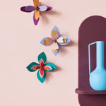 Studio Roof Lavender Cocktail craft flowers set hanging on a pink wall next to a blue vase