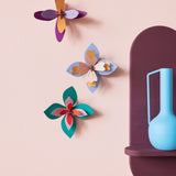 Studio Roof Lavender Cocktail craft flowers set hanging on a pink wall next to a blue vase