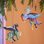 2 Studio Roof DIY card Pegasus Christmas tree decorations hanging in front of an orange background