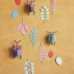 Studio Roof 3D card wall decoration bugs on a yellow wall surrounded by card leaves