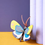 Studio roof colourful yellow monarch butterfly cardboard wall decoration leaning against some light purple tubes on an orange floor