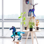 Studio roof eco-friendly slotting animal totem models stood on some wooden furniture next to some potted plants in front of a bright window