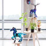 Studio roof eco-friendly slotting animal totem models stood on some wooden furniture next to some potted plants in front of a bright window