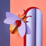 Studio roof art and craft bumble bee decoration climbing on a red arch way in front of a purple background