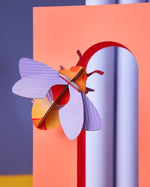 Studio roof art and craft bumble bee decoration climbing on a red arch way in front of a purple background