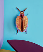 Studio Roof 3D cardboard Cuprum beetle craft kit displayed on a wall 