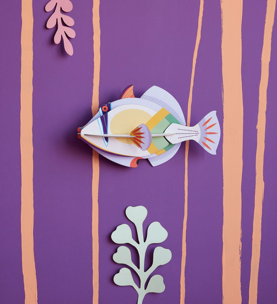 Studio Roof Picasso fish plastic-free wall decoration on a purple wall next to some card plants