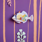 Studio Roof Picasso fish plastic-free wall decoration on a purple wall next to some card plants