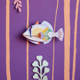 Studio Roof Picasso fish plastic-free wall decoration on a purple wall next to some card plants