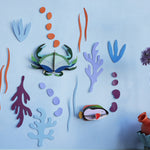 Studio Roof plastic-free craft sea creature wall decorations on a white background next to a potted plant