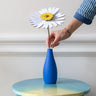 Studio Roof daisy everlasting flower cardboard flower decoration shown built and being placed in a blue vase.
