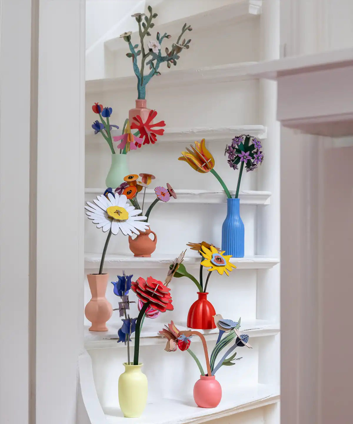 Studio Roof everlasting flower decoration craft kit collection showing various flower varies built and displayed in small vases and placed on white painted steps.