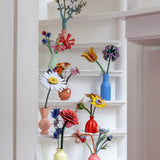 Studio Roof everlasting flower decoration craft kit collection showing various flower varies built and displayed in small vases and placed on white painted steps.
