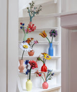 Studio Roof everlasting flower decoration craft kit collection showing various flower varies built and displayed in small vases and placed on white painted steps.