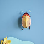 Studio Roof Lemon Fruit Beetle decoration hung up on a blue painted wall