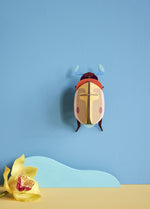 Studio Roof Lemon Fruit Beetle decoration hung up on a blue painted wall