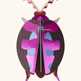 A Studio Roof 3D lumen pink beetle cardboard wall art fully assembled with a metallic finish on the pieces.
