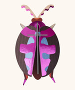 A Studio Roof 3D lumen pink beetle cardboard wall art fully assembled with a metallic finish on the pieces.