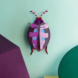 Studio Roof 3D cardboard lumen pink beetle craft kit displayed on a wall 
