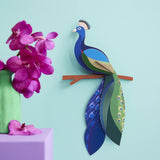A Studio Roof 3D paradise peacock bird perched on a branch displayed on a wall