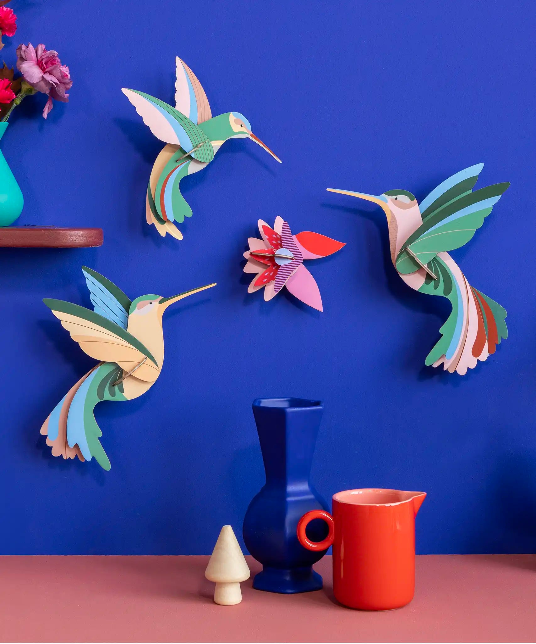 Studio Roof Dance of Hummingbirds Paradise Bird Set wall art kit assembled and displayed on a blue wall.