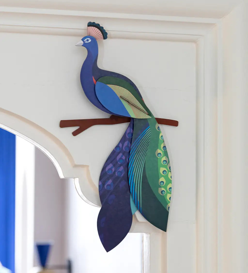 A Studio Roof 3D paradise peacock bird perched on a branch displayed on a window frame