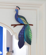 A Studio Roof 3D paradise peacock bird perched on a branch displayed on a window frame
