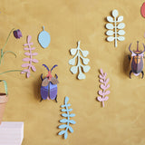 Studio Roof card craft bugs hanging on a yellow wall next to a potted plant