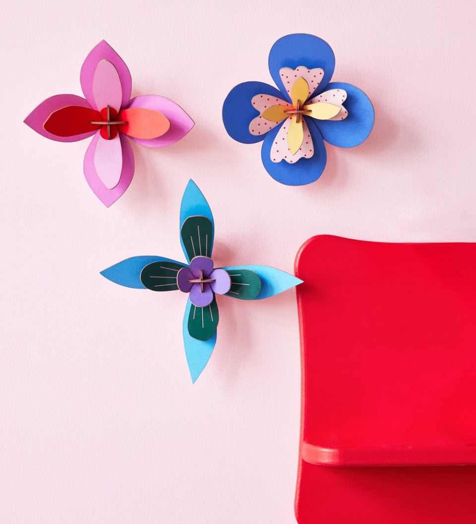 3 Studio Roof plastic-free craft flowers hung on a pink wall next to a red painted shelf