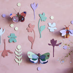 Studio Roof Winged Medley DIY wall decorations on a pink wall next to a large potted plant