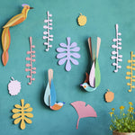 Studio Roof plastic-free card bird wall decorations on a blue wall next to some potted plants