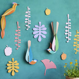 Studio Roof plastic-free card bird wall decorations on a blue wall next to some potted plants