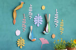Studio Roof plastic-free card bird wall decorations on a blue wall next to some potted plants