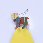 Close up of a Studio Roof renewable flat-pack bear decoration balance on top of a yellow wooden board against a blue wall