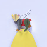 Close up of a Studio Roof renewable flat-pack bear decoration balance on top of a yellow wooden board against a blue wall