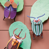 3 Studio roof slotting craft model beetles climbing on some green model leaves on a brown background