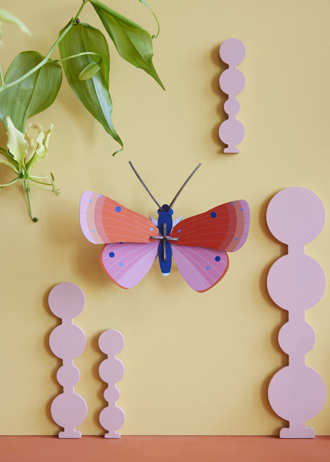 Studio Roof Speckled Copper Butterfly decoration on a pastel yellow coloured painted wall