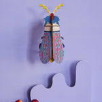 Studio Roof Striped Wing Beetle hung up on a purple wall