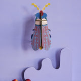 Studio Roof Striped Wing Beetle hung up on a purple wall